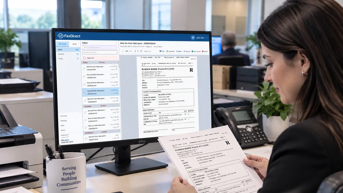 A front-desk administrator reading a received fax in FaxDirect while holding the printed copy